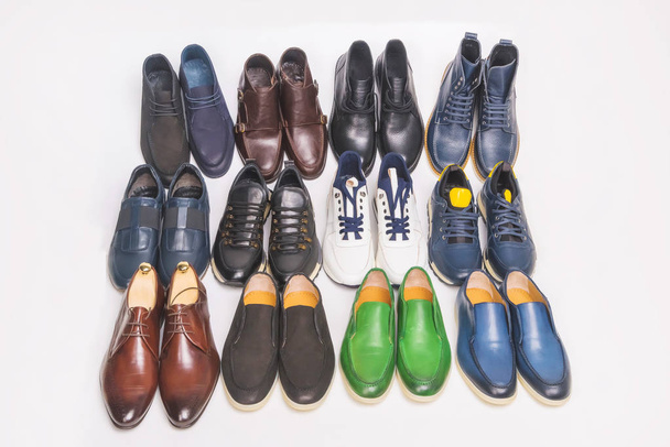 Zapatos de hombre multicolores sobre fondo blanco. Muchos zapatos de hombre seguidos. Tipos de zapatos masculinos. Botas, zapatillas y zapatos
 - Foto, imagen
