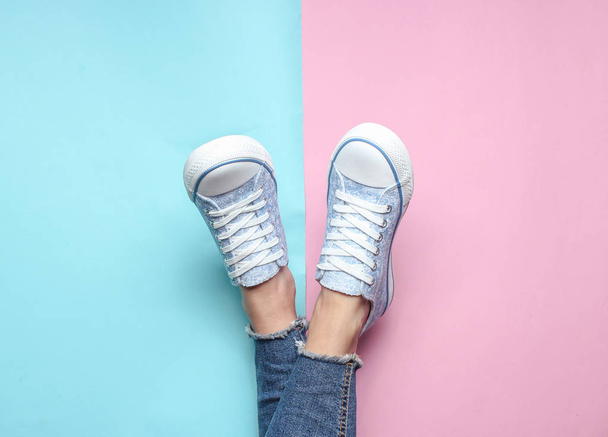 Ženské nohy v těsné, roztrhané džíny, tenisky na růžovém pozadí modré pastelové. Pohled shora, minimalismus, kopie spac - Fotografie, Obrázek