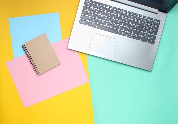 Laptop, Notizbuch auf farbigem Pastell-Hintergrund, moderner Arbeitsplatz, Minimalismus, flacher Lagestil, Top-Ausstattung - Foto, Bild