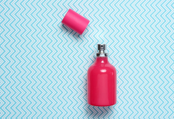 Червона пляшка парфумів на творчому синьому фоні, мінімалізм, вид зверху
 - Фото, зображення