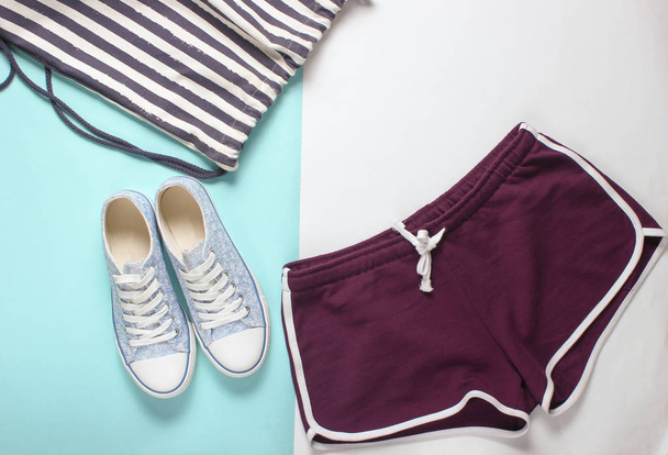 Women's clothing and accessories for fitness on a colored pastel background. Sneaker, sports shorts, bag. Flat lay style. Top vie - Photo, Image