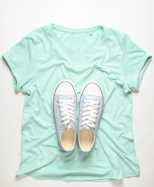 Модные кроссовки лежат на футболке на белом фоне, минимализм, топ-ви
 - Фото, изображение