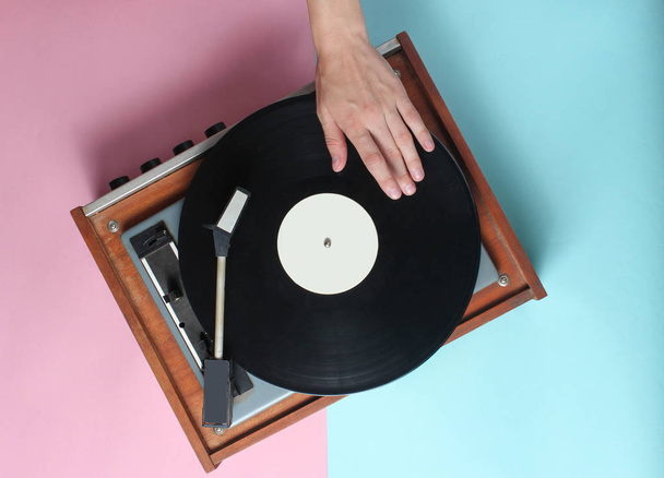 As mãos femininas usam o jogador de vinil retrô em um fundo pastel rosa azul. DJ. Topo Vie
 - Foto, Imagem
