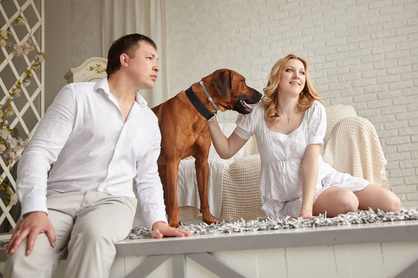 happy young couple with their pet sitting on the living room floor. - Φωτογραφία, εικόνα