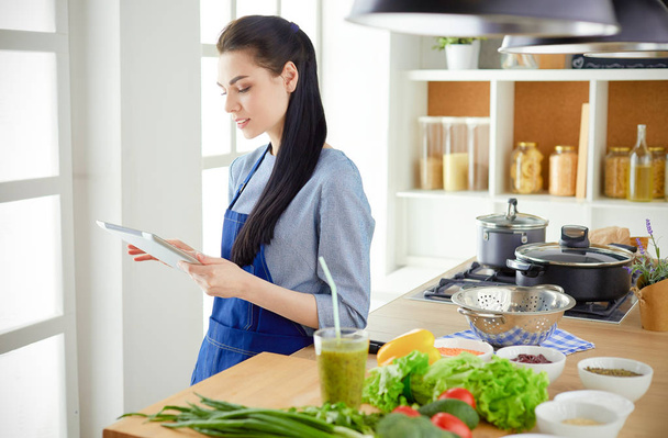 Young woman using a tablet computer to cook in her kitchen - Foto, Imagem