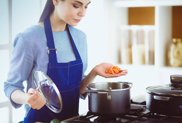 Cooking woman in kitchen with wooden spoon - Photo, Image