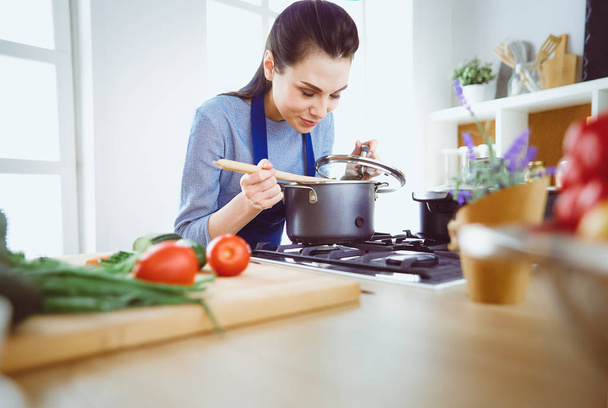Cooking woman in kitchen with wooden spoon - Foto, Imagen