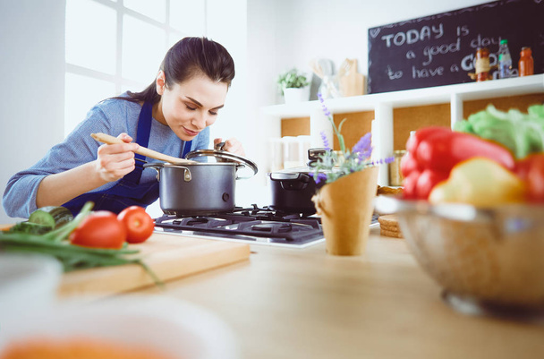 Cooking woman in kitchen with wooden spoon - Φωτογραφία, εικόνα