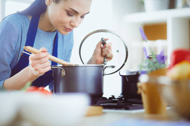 Cooking woman in kitchen with wooden spoon - Foto, afbeelding