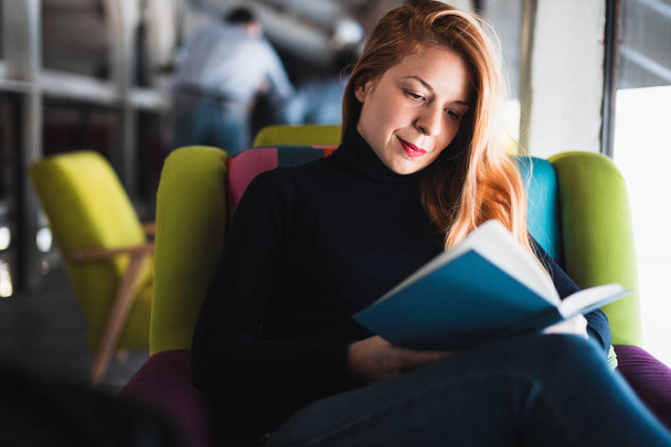 Jeune femme assise dans un café lisant un livre
 - Photo, image