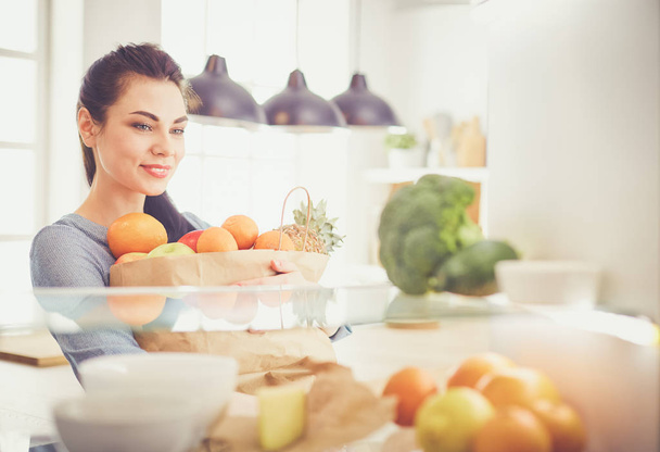 Smiling woman taking a fresh fruit out of the fridge, healthy food concept - Фото, изображение