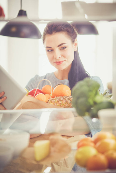 Smiling woman taking a fresh fruit out of the fridge, healthy food concept - 写真・画像