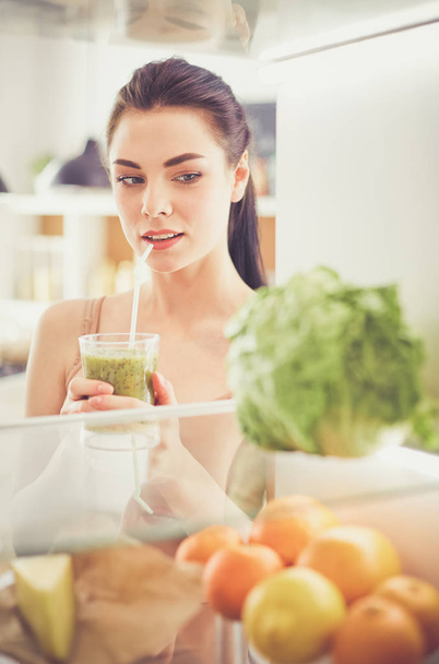 lächelnde Frau holt frisches Gemüse aus dem Kühlschrank, gesundes Ernährungskonzept - Foto, Bild