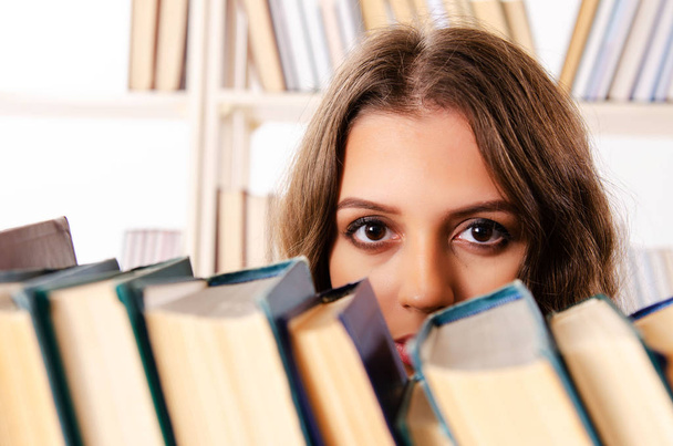 Jonge vrouwelijke student bereidt examens in de bibliotheek voor - Foto, afbeelding