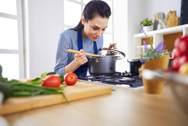 Cooking woman in kitchen with wooden spoon - Foto, Bild