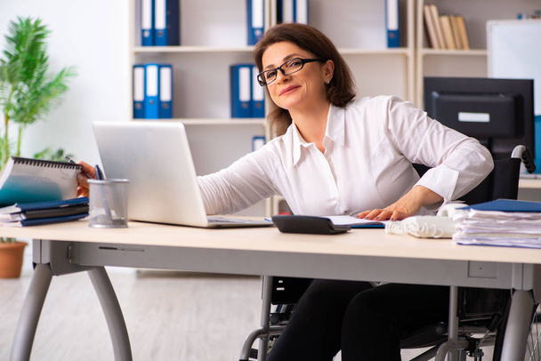 Жінка-працівник в інвалідному кріслі в офісі
 - Фото, зображення
