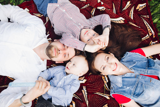 Above view of happy family lying in park together with kids and smiling. - Foto, immagini