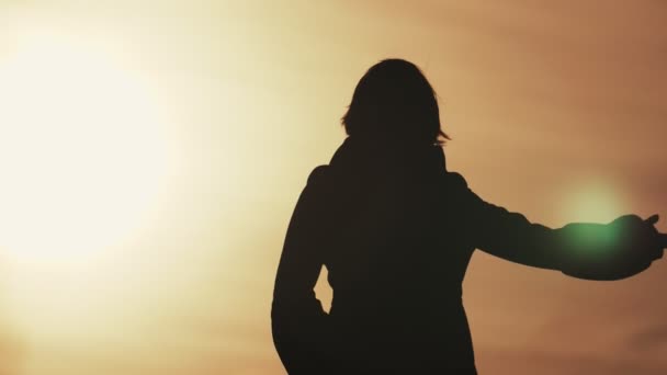 Stylish woman dancing with her hands elegantly at sunset in spring in slo-mo                              Artistic back view of an elegant woman dancing with her flexible hands in a horizonless field at dark cloudy sunset in spring in slow motion - Footage, Video