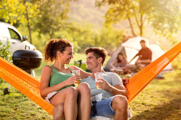 Smiling couple enjoying in hammock chair on camping trip - Foto, afbeelding