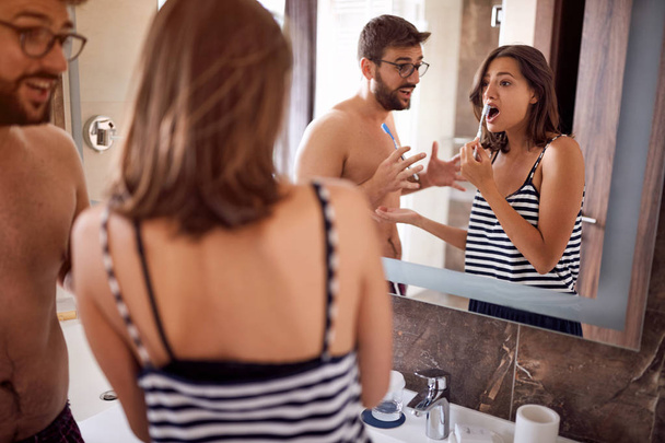 Attractive young couple brushing teeth in morning - Foto, imagen