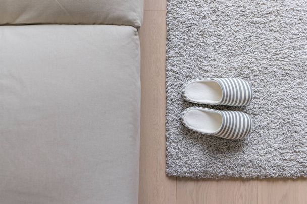 Тапочки на сером ковре на полу дома
 - Фото, изображение