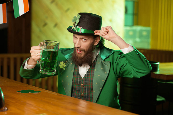 Dark-haired bearded young man in a leprechaun hat looking amused - Photo, Image