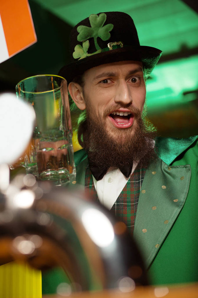 Dark-haired bearded young man in a leprechaun costume feeling wonderful - Foto, imagen