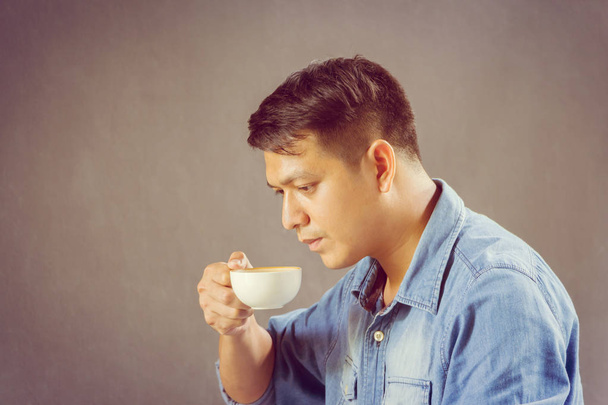 Close-up of a young business engineering man in blue jeans having coffee and looking laptop - Foto, immagini