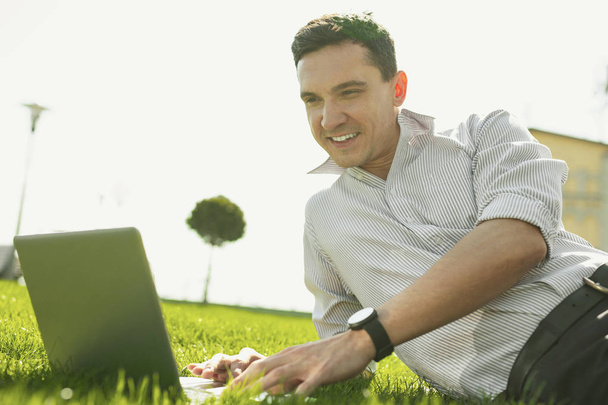 Smart smiling man enjoying his work in park - Foto, Imagem