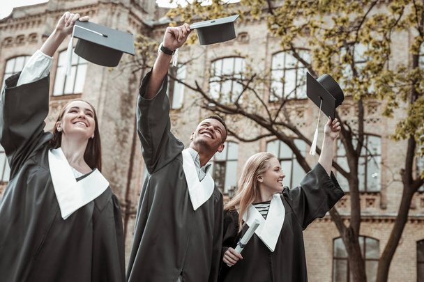 Positive delighted leavers raising their graduation hats - Valokuva, kuva
