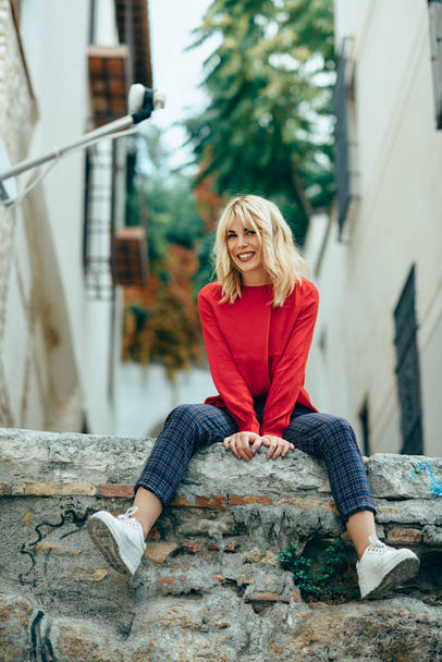 Lächelndes blondes Mädchen mit rotem Hemd genießt das Leben im Freien. - Foto, Bild