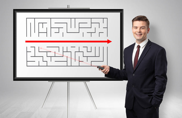 Businessman presenting potential exit from a labyrinth - Fotoğraf, Görsel