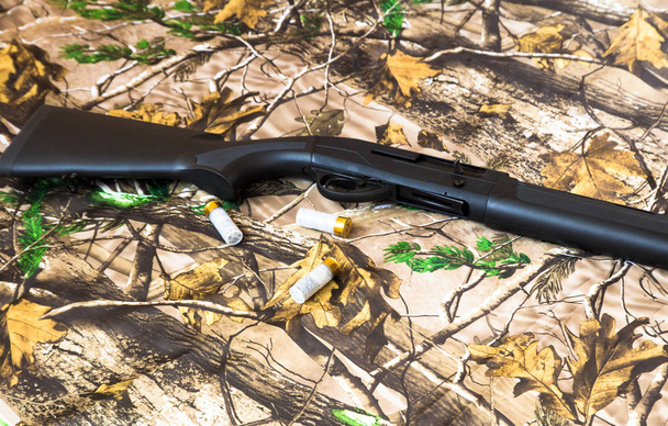zwarte Shotgun van 12 gauge en cartridges op de camouflage achtergrond - Foto, afbeelding