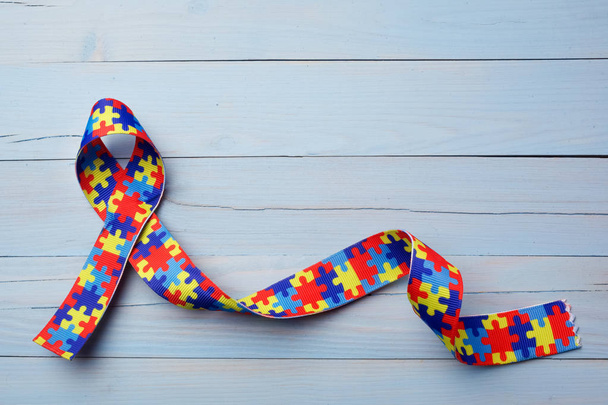 World Autism awareness and pride day or month with Puzzle pattern ribbon on blue wooden background. - Fotoğraf, Görsel