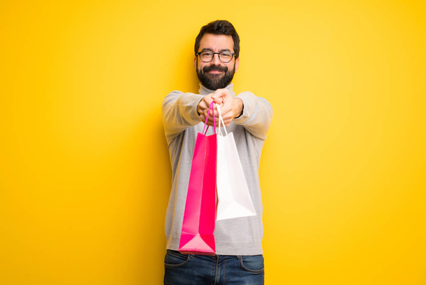 Mann mit Bart und Rollkragen hält viele Einkaufstüten in der Hand - Foto, Bild