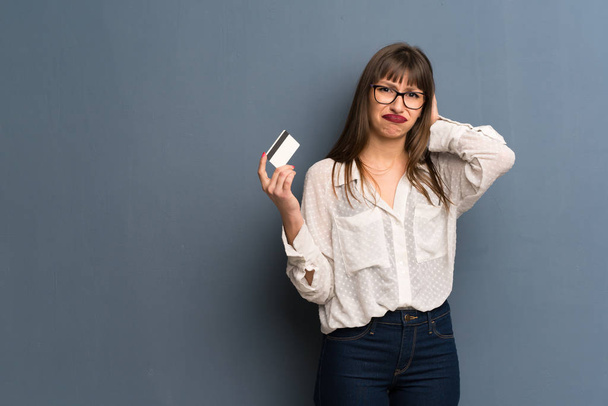 Donna con gli occhiali sopra il muro blu che prende una carta di credito senza soldi
 - Foto, immagini