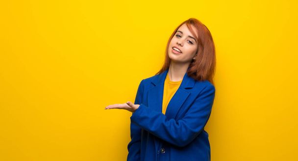 Young redhead woman with trench coat presenting an idea while looking smiling towards - Photo, Image