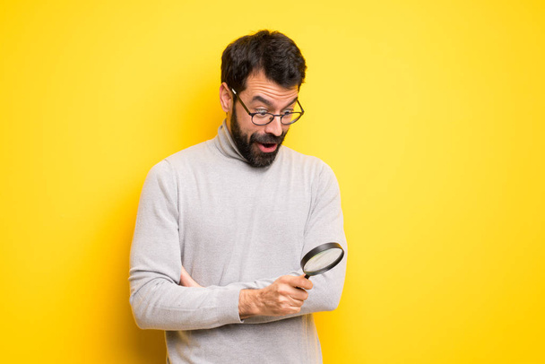 Man with beard and turtleneck holding a magnifying glass - Photo, Image