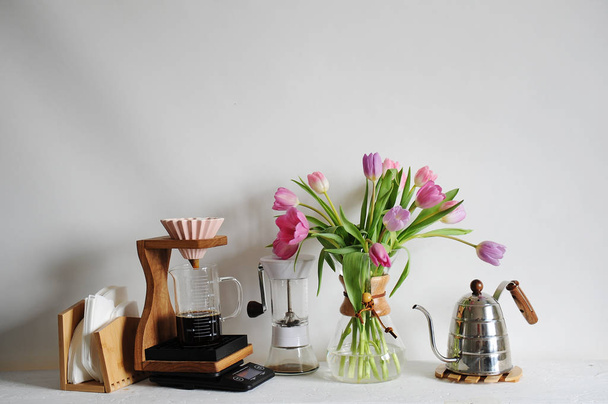 Bukiet tulipanów w karafka kawa na biały stół. Instrukcja parzenia z ociekiem origami, filtr papierowy - Zdjęcie, obraz