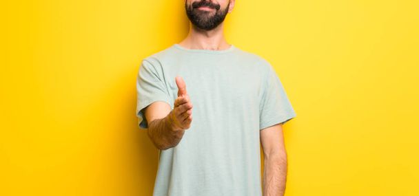 Uomo con barba e camicia verde che stringe la mano per chiudere un buon affare
 - Foto, immagini