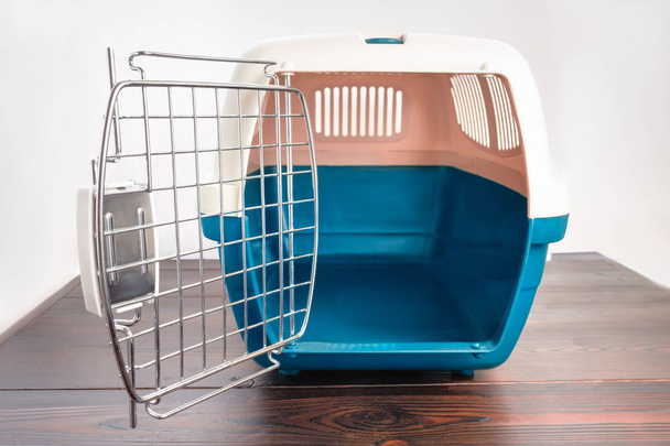 Πλαστικό κλουβί μεταφοράς για σκύλους και γάτες σε ένα ξύλινο τραπέζι. Ταξιδιωτικές μεταφορές, κτηνιατρική κλινική και κατοικίδιο ζώο φροντίζω έννοια - Φωτογραφία, εικόνα