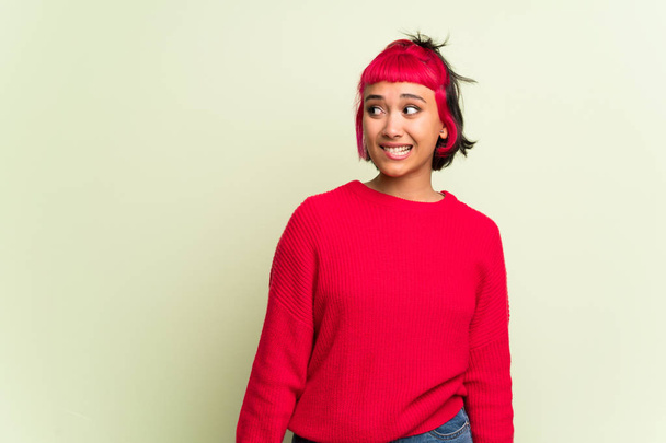 Young woman with red sweater is a little bit nervous and scared pressing the teeth - Photo, Image