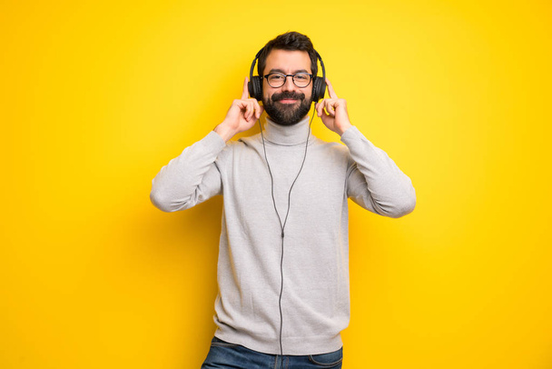 Homme à barbe et col roulé écoutant de la musique avec écouteurs
 - Photo, image