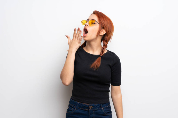 Young redhead woman over white wall yawning and covering wide open mouth with hand - Photo, Image