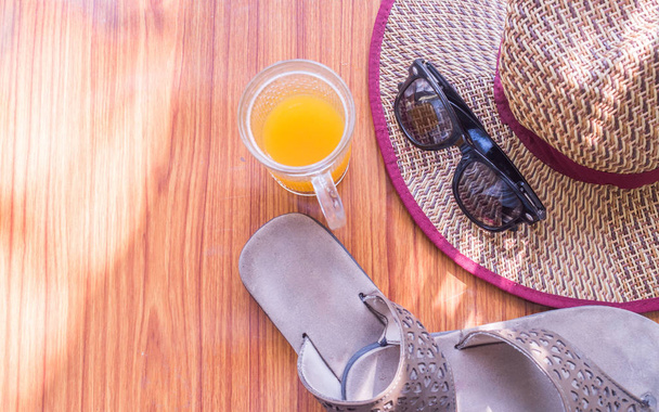 Ready to travel. Top view beach background of essential modern summer women accessories in wooden table. Sunglasses, Straw hat, flip flops, with a glass of lime juice. Copy space Room for text on left - Photo, Image