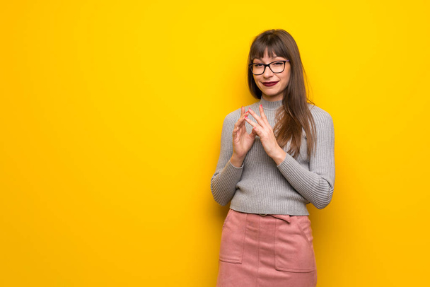 Vrouw met bril over gele muur gekonkel iets - Foto, afbeelding