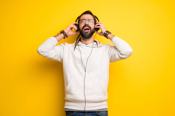 Hippie man with dreadlocks listening to music with headphones - Foto, Imagen