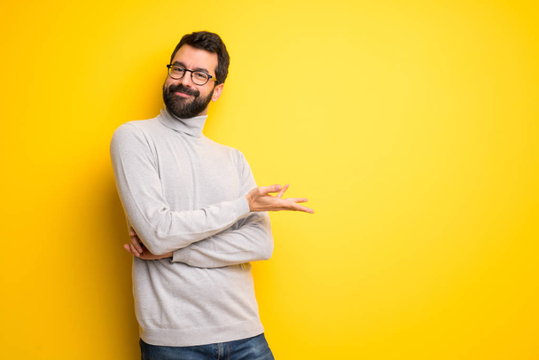 Man with beard and turtleneck presenting an idea while looking smiling towards - Photo, Image