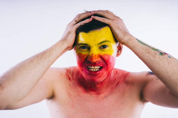 young man with painted yellow red face. Soccer fan - Zdjęcie, obraz