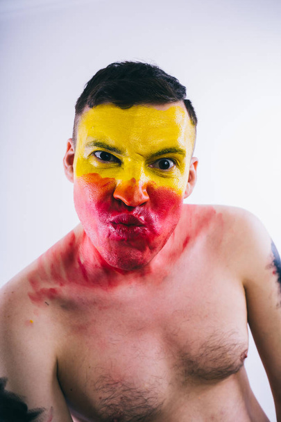young man with painted yellow red face. Soccer fan - Foto, Imagen